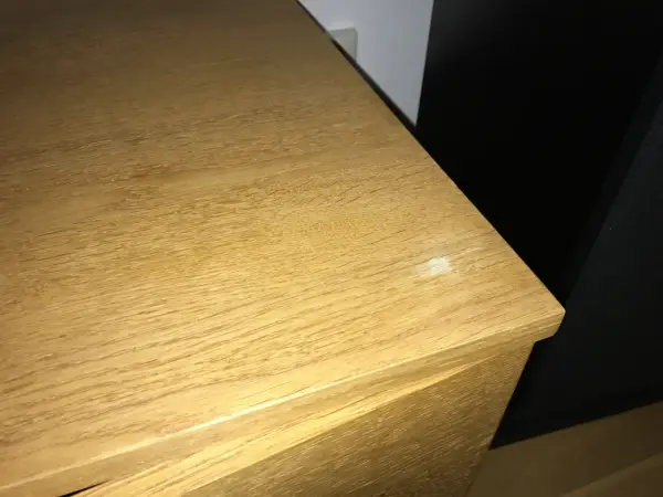 En ljus träyta, kanske ett fanerbord, med en liten vit fläck som behöver slipas.