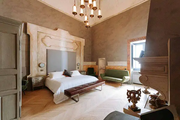 Ett lyxigt sovrum med en stor säng, grön soffa och en imponerande eldstad. Perfekt hotell inredning inspiration för ett elegant hem.