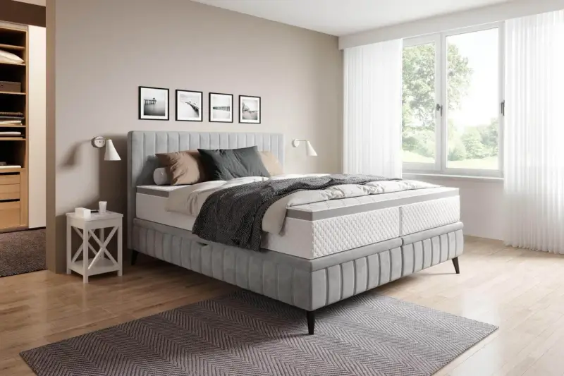 Sovrum med en stor säng i grått tyg. En fin balans att blanda beige och grått inredning med detaljer i trä och svarta tavlor på väggen.
